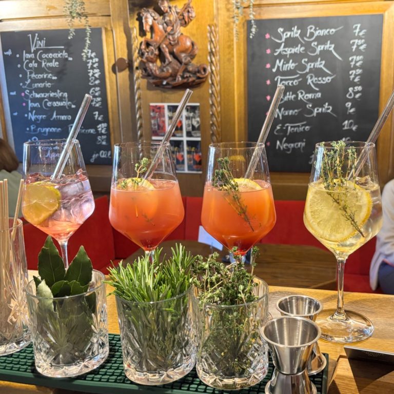 Verschiedene Spritz-Getränke in Gläsern auf einer Bar.